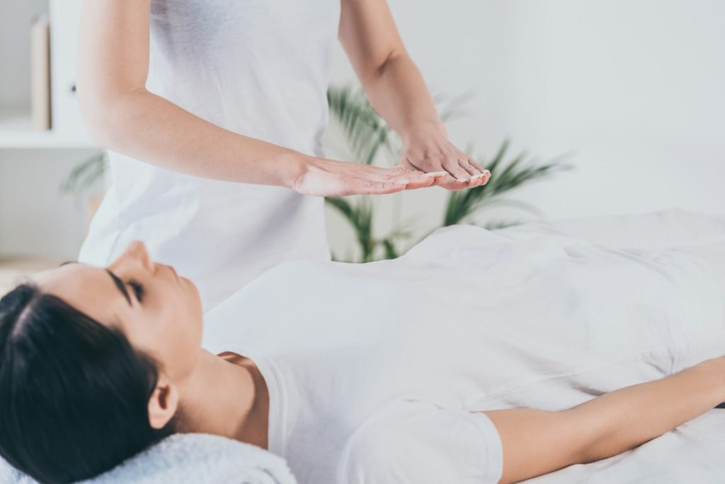 cropped shot of peaceful young woman receiving reiki healing treatment